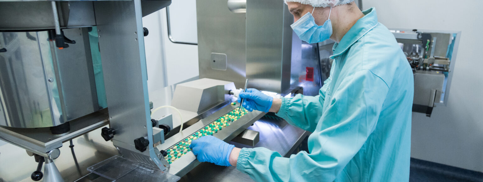 Pharmaceutical technician in sterile environment working on production of pills at pharmacy factory